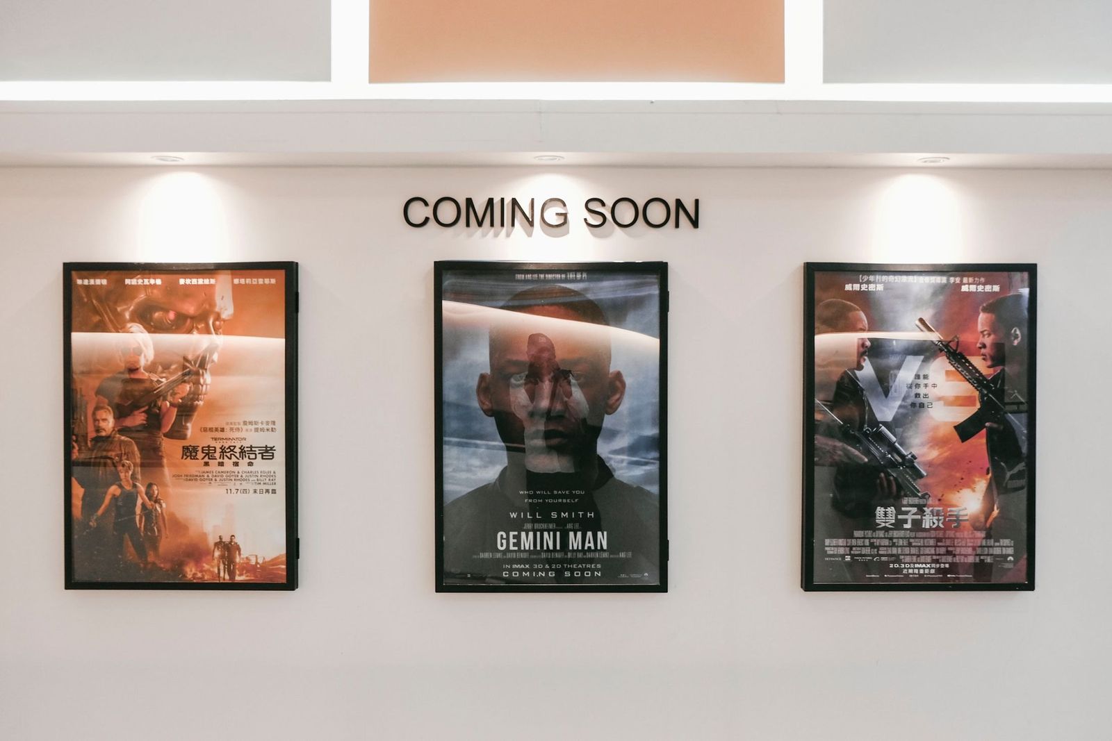 Filmplakate im Kinoflur unter dem Schild „Coming Soon“